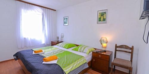 a bedroom with a bed and a chair and a window at Antunovic in Veli Lošinj