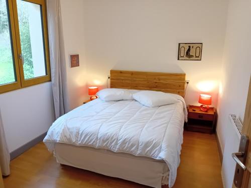 Un dormitorio con una cama con sábanas blancas y dos lámparas. en La Bertrandie, en Florimont-Gaumiers