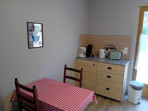 Una cocina con una mesa y una cómoda con una mesa a cuadros rojos. en La Bertrandie, en Florimont-Gaumiers