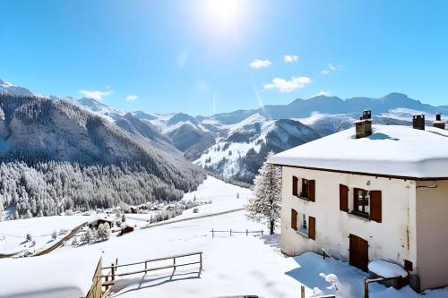 una casa nella neve con montagne sullo sfondo di Casa-La Fuste centre Saint-Véran ski au pied a Saint-Véran