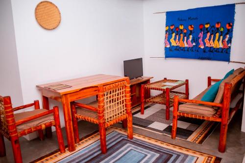 ein Raum mit Tisch und Stühlen und einem Laptop in der Unterkunft The Hub Train House Apartments in Zanzibar City