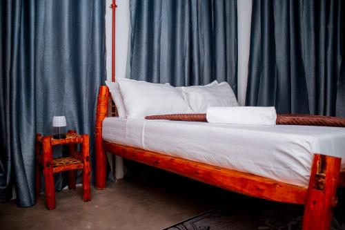 1 dormitorio con cama de madera y cortinas azules en The Hub Train House Apartments, en Zanzíbar