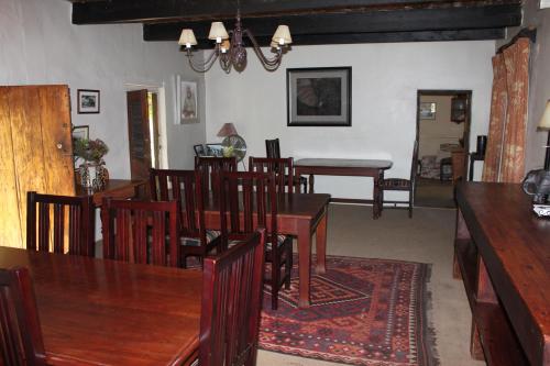 a dining room with wooden tables and chairs at Leeuwenbosch Shearers Lodge - Amakhala Game Reserve in Buyskloof