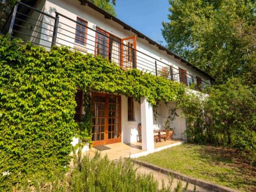 Die Ou Pastorie في هارتبيسبورت: منزل مغطى باللبلاب وباب خشبي