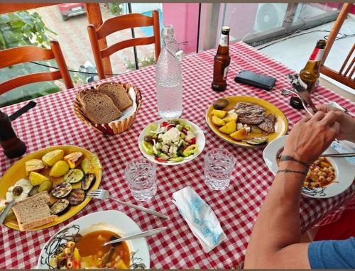 Eine Frau, die mit Essen und Getränken am Tisch sitzt. in der Unterkunft SuperPanorama GuestHouse in Kukës