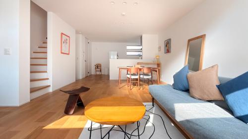a living room with a blue couch and a table at USJ 梅田 大阪城へ直通 駐車場付きモダン一軒家 JR弁天町駅3分 LIRI Aoi in Osaka