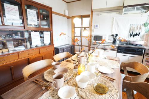 a kitchen with a wooden table with white dishes on it at Max 29 ppl, Entire building, near ski resort,16 beds, 4 futons ,Washer and dryer!! in Yuzawa