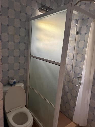 a bathroom with a toilet and a glass shower door at Akure Airport Hotel in Oba Ile