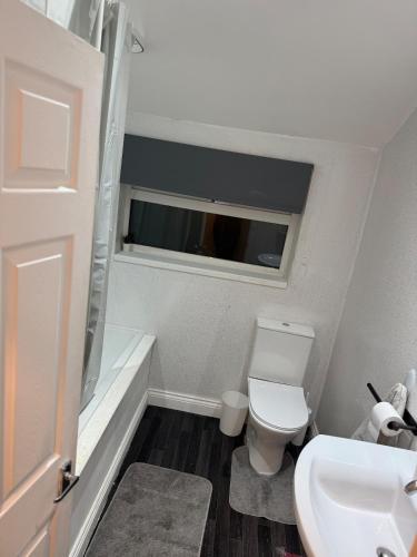 a bathroom with a toilet and a sink and a window at 4Bed Grimsby Contractor Work Crew Stay in Grimsby