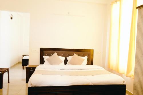 a bedroom with a large bed with white sheets at Dhananjay home stay in Dharampur