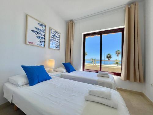 two beds in a room with a large window at Luxury, Frontline Burriana Beach, Nerja in Nerja