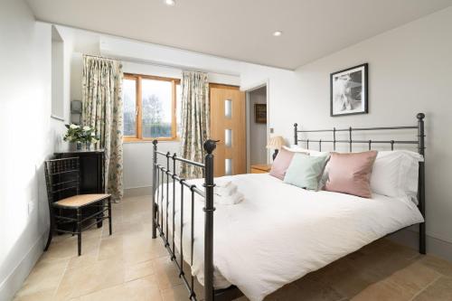a bedroom with a black bed with white and pink pillows at Barn Cottage Painswick in Painswick
