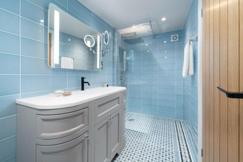 a blue bathroom with a sink and a mirror at Barn Cottage Painswick in Painswick