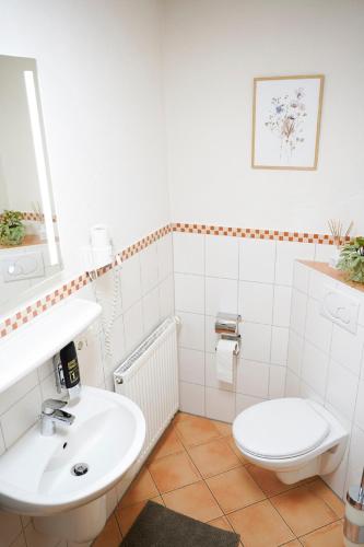 a white bathroom with a sink and a toilet at Restaurant - Garni bei Peppo in Ebern