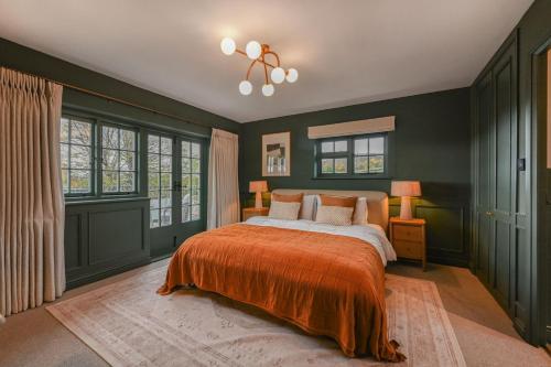 a bedroom with green walls and a bed with an orange blanket at Merryweather in Canterbury