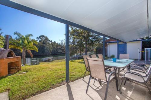 a patio with a table and chairs and a yard at Waterfront Wonder - lakeside home w. private jetty in Conjola