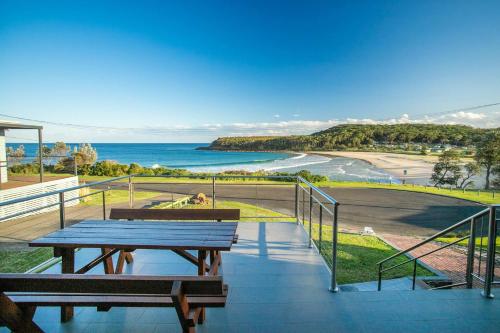 a balcony with a picnic table and a view of the ocean at Surfside in Kioloa