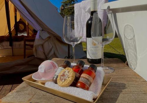 Kanimbia Luxury Glamping في Obi Obi: صينية مع زجاجة من النبيذ وكأس