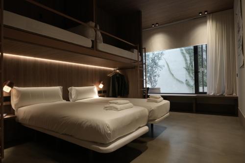 Un dormitorio con dos camas y una gran ventana. en CASA ROMA Hostel Boutique, en Tarragona