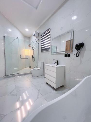 a white bathroom with a tub and a sink and a shower at Casa Lumière in Lekki