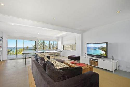 a living room with a couch and a flat screen tv at Sticks by the Sea - pet-friendly coastal home in Manyana