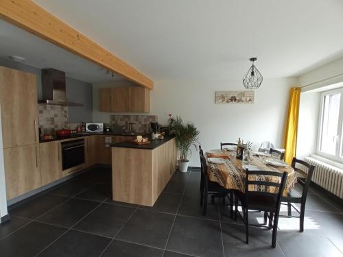 una cucina e una sala da pranzo con tavolo e sedie di Entre Dômes et Sancy - Le moderne a Perpezat