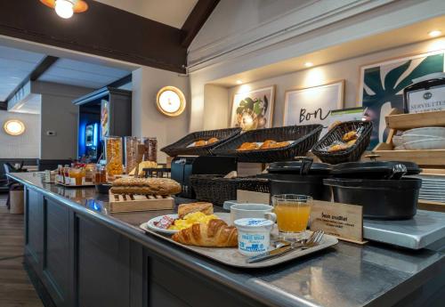 B&B HOTEL Niort Sud Venise Verte في نيورْ: بوفيه إفطار مع خبز ومشروبات على طاولة