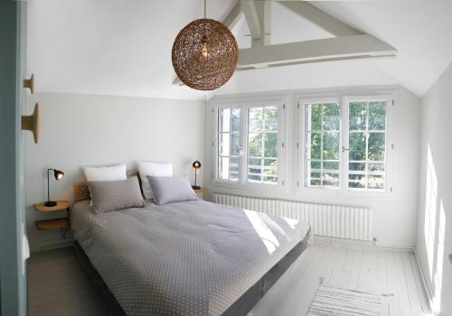 a white bedroom with a bed and a large window at LE CEDRE Maison bord de LOIRE 4 in Muides-sur-Loire