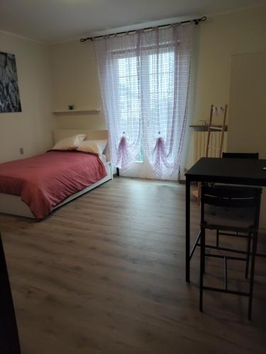 a bedroom with a bed and a desk and a window at Malpensa monolocale indipendente in Samarate
