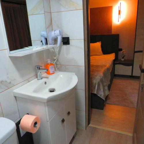 a bathroom with a sink and a bedroom with a bed at Casa Alex in Topliţa