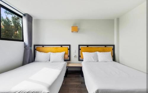 two beds in a room with white walls at Kamya cottage in New Delhi