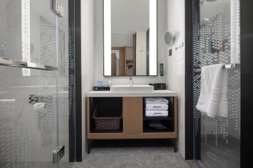 a bathroom with a sink and a mirror and a shower at Hampton by Hilton Cixi Guanhaiwei in Ningbo