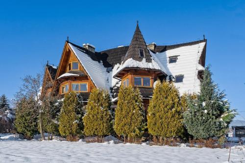 una casa cubierta de nieve con árboles delante en Osada Białka Tatrzańska - apartamenty & domki z ogrodem dla rodzin Odkryj-Bialke, en Białka Tatrzanska