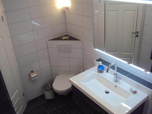 a bathroom with a white toilet and a sink at Ferienwohnung Krabbe in Hooksiel