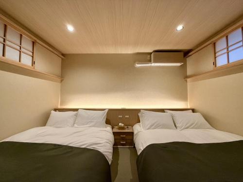 two beds in a small room with at NEW Hotel Komugi Skytree - modern Japanese-style guesthouse near Asakusa & Skytree 3mins, whole house rental perfect for large groups up to 14pax in Tokyo