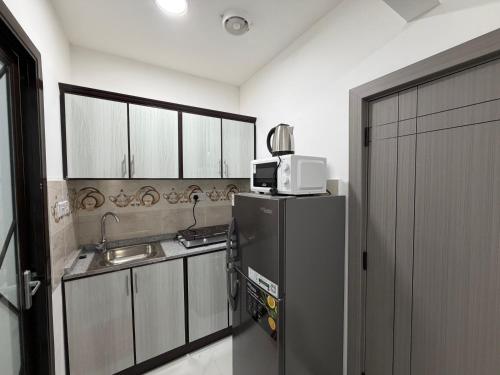 a kitchen with a black refrigerator and a sink at Al-Manaseer Studio in Abu Dhabi