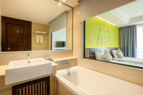Bay Beach Resort Jomtien في جومتين بيتش: حمام مع حوض ومرآة كبيرة