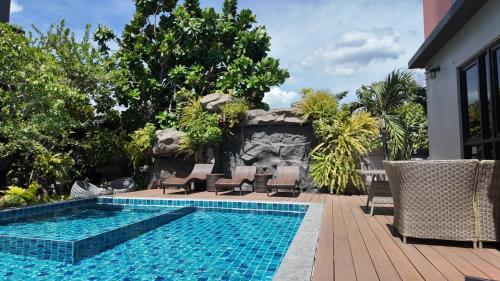 a swimming pool next to a patio with chairs at Bangkok Boutique Resort Rangsit in Pathum Thani