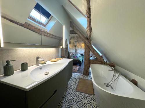 Un baño con bañera, lavabo y bañera. en La Maison Labonnechose - Piscine chauffée - Calme - Jeux, en Notre-Dame-de-Fresnay