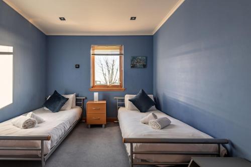 2 Betten in einem Zimmer mit blauen Wänden und einem Fenster in der Unterkunft Homeview - Elie & Earlsferry in Elie