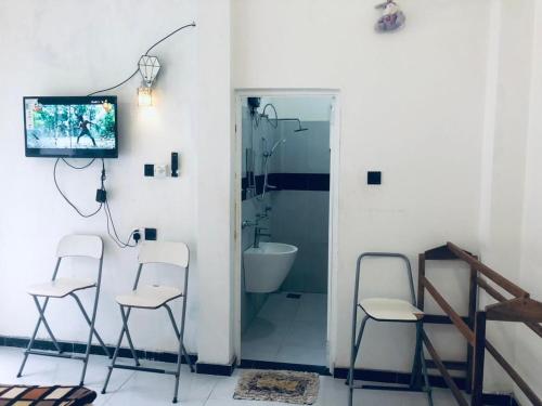 Un baño con dos sillas y una ducha y un televisor. en Thisara Pool Hotel Kataragama & Yala-Kabilththa Jeep Tour, en Kataragama