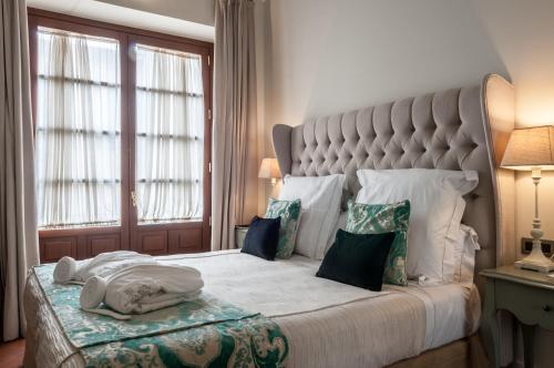 una camera da letto con un grande letto con una grande testiera di Palacio Pinello a Siviglia