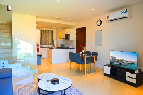 sala de estar con TV y mesa y cocina en Wateera Jebel Sifah-Beachfront, en As Sīfah