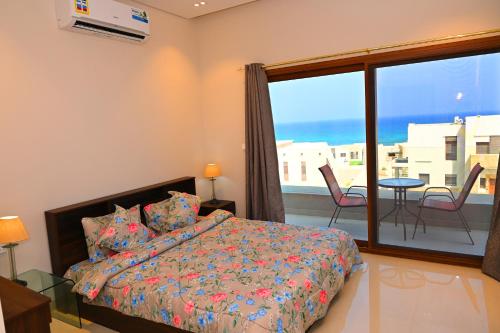 Un dormitorio con una cama y un balcón con vistas. en Wateera Jebel Sifah-Beachfront, en As Sīfah