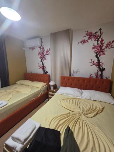 Beachfront Central Apartments في دوريس: سريرين في غرفة بها زهور على الحائط