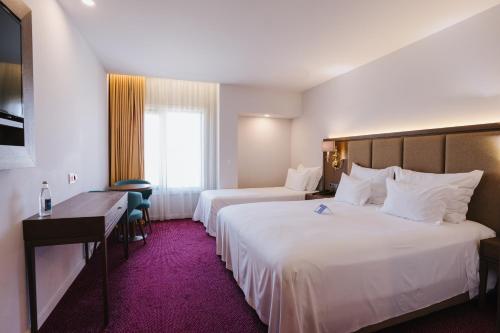 a hotel room with two beds and a desk at Hotel Premium Chaves - Aquae Flaviae in Chaves