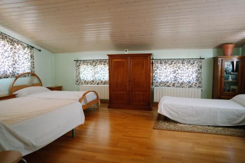 two beds in a room with wooden floors and windows at Casa Rural Álvarez in Caravaca de la Cruz