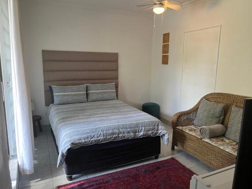 a bedroom with a bed and a couch at Welcoming One Bedroom Flatlet with Pool in Pietermaritzburg