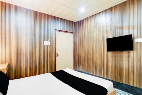 ein Schlafzimmer mit einem Bett und einem Fernseher an der Wand in der Unterkunft Hotel O Nepali Mandir Bus Terminal Formerly Hotel Aaghnya in Guwahati