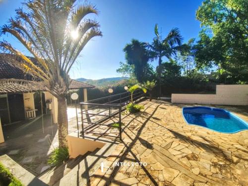 uma palmeira em frente a uma piscina em Chácara c/ Piscina, Churrasqueira com vista linda em Poços de Caldas